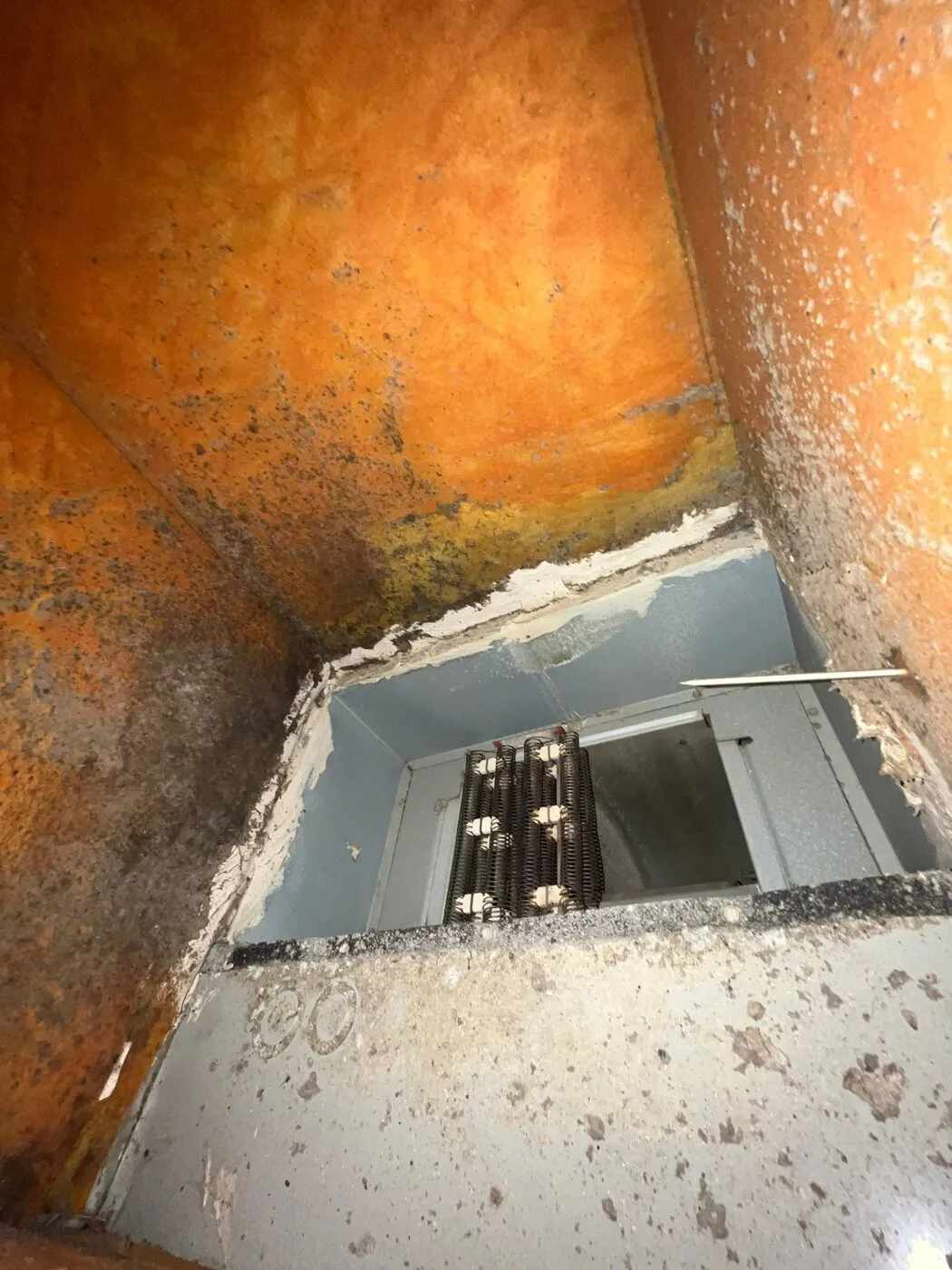Return box with exposed fiberglass lining and the coil visible below