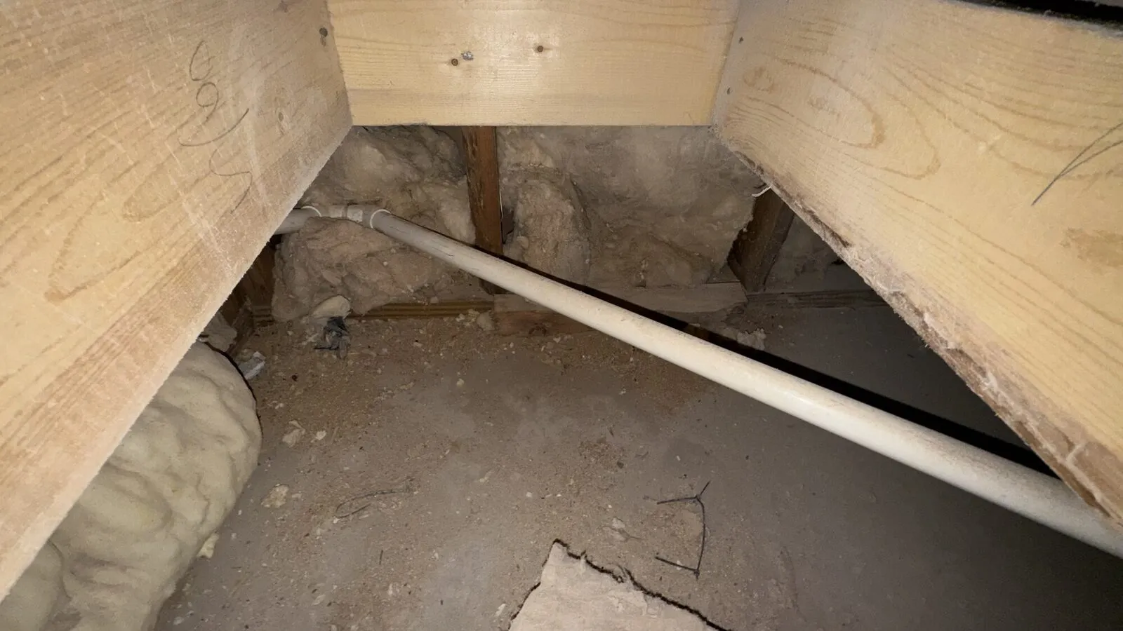 Old batts with a gap along the joist and a pipe run through the void