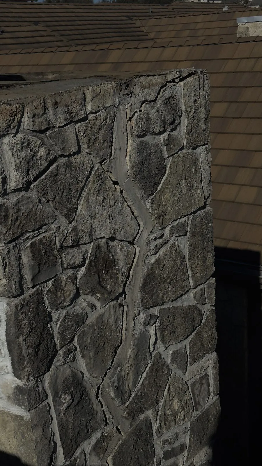 Stone chimney with cracks opening in the mortar joints