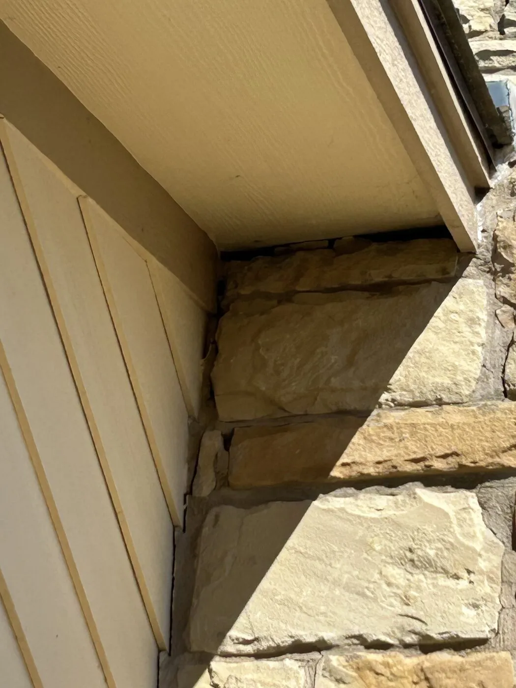 Where the stone chimney meets the roofline and the eave